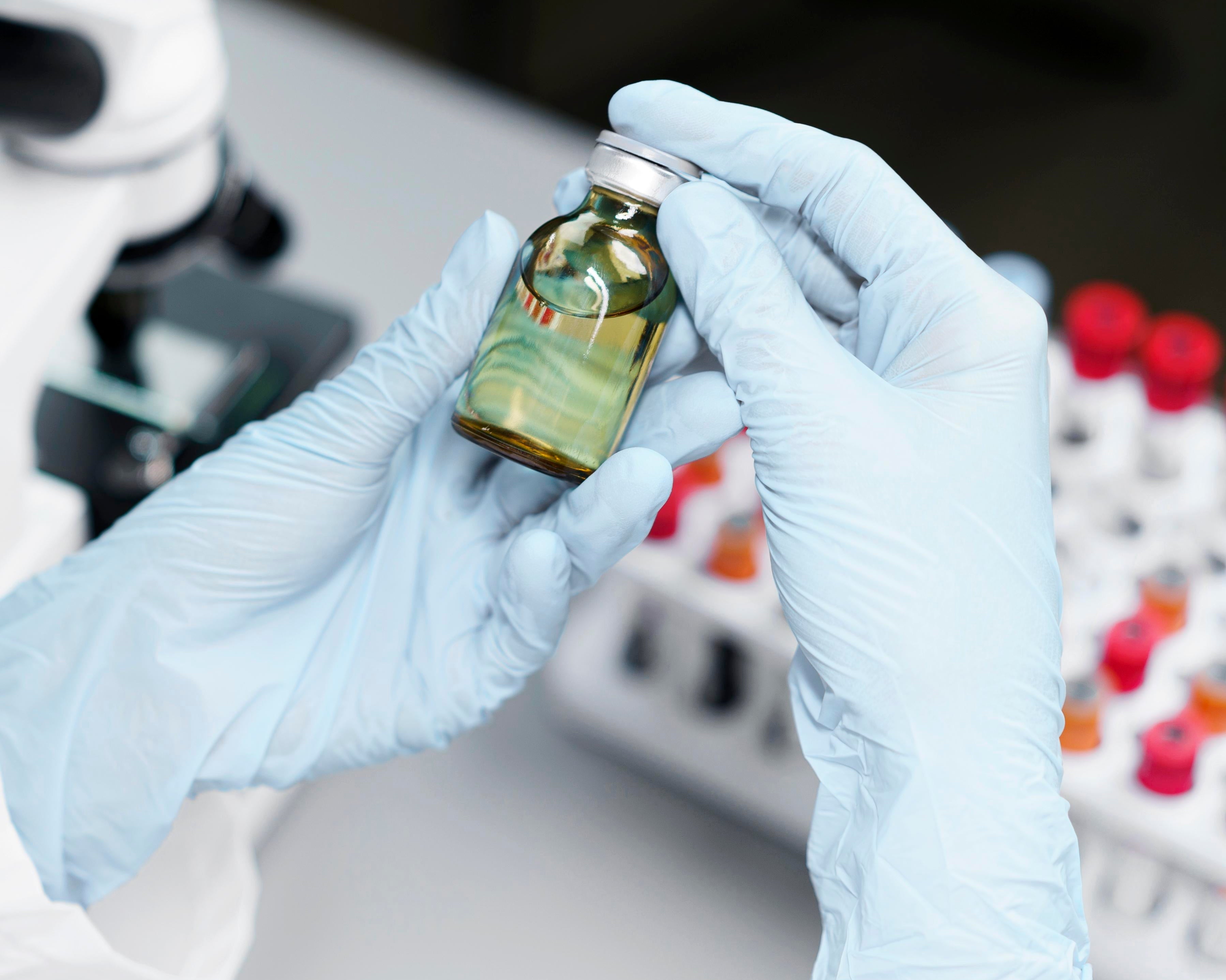 mani di un medico che tengono boccetta di olio di cbd e provette sullo sfondo