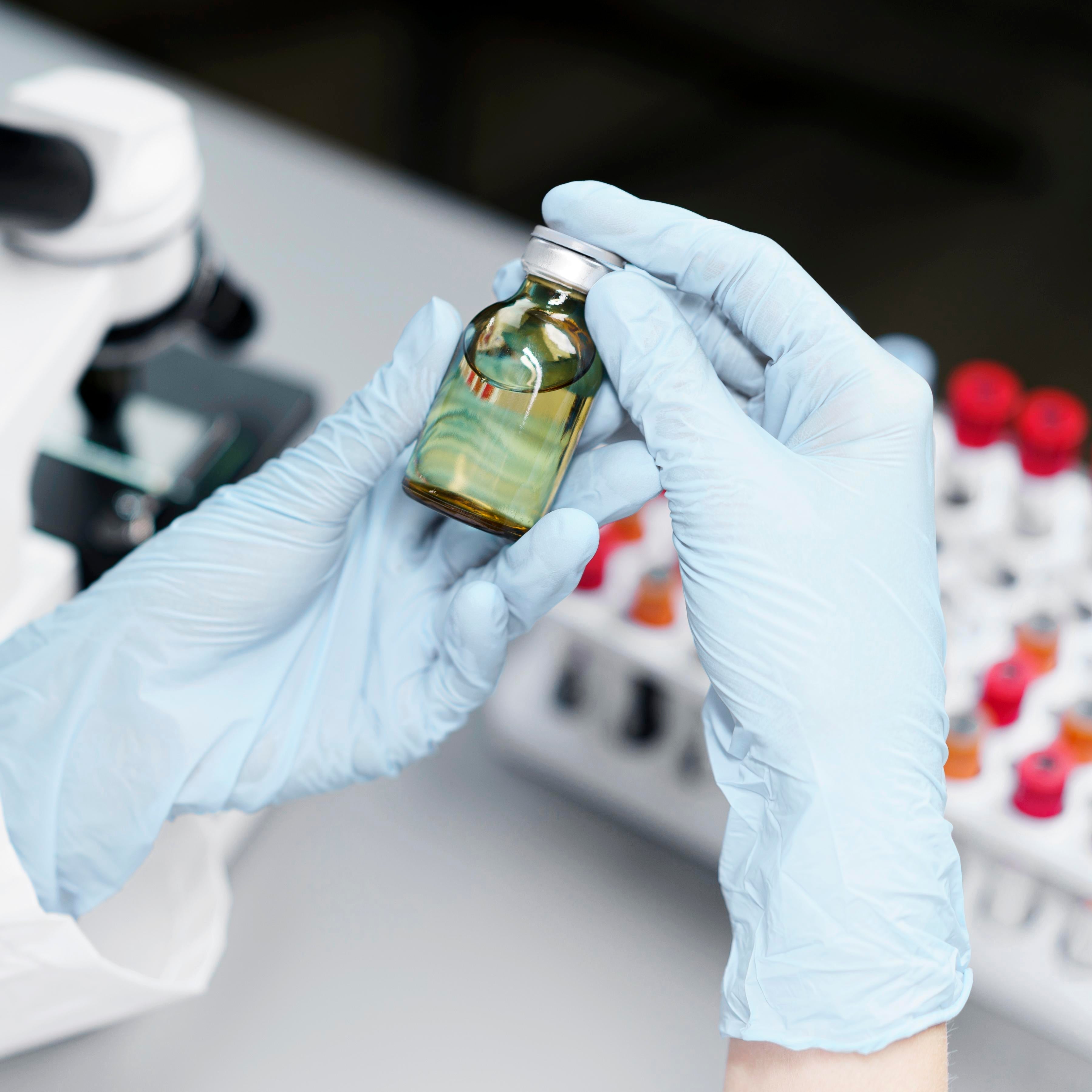 mani di un medico che tengono boccetta di olio di cbd e provette sullo sfondo